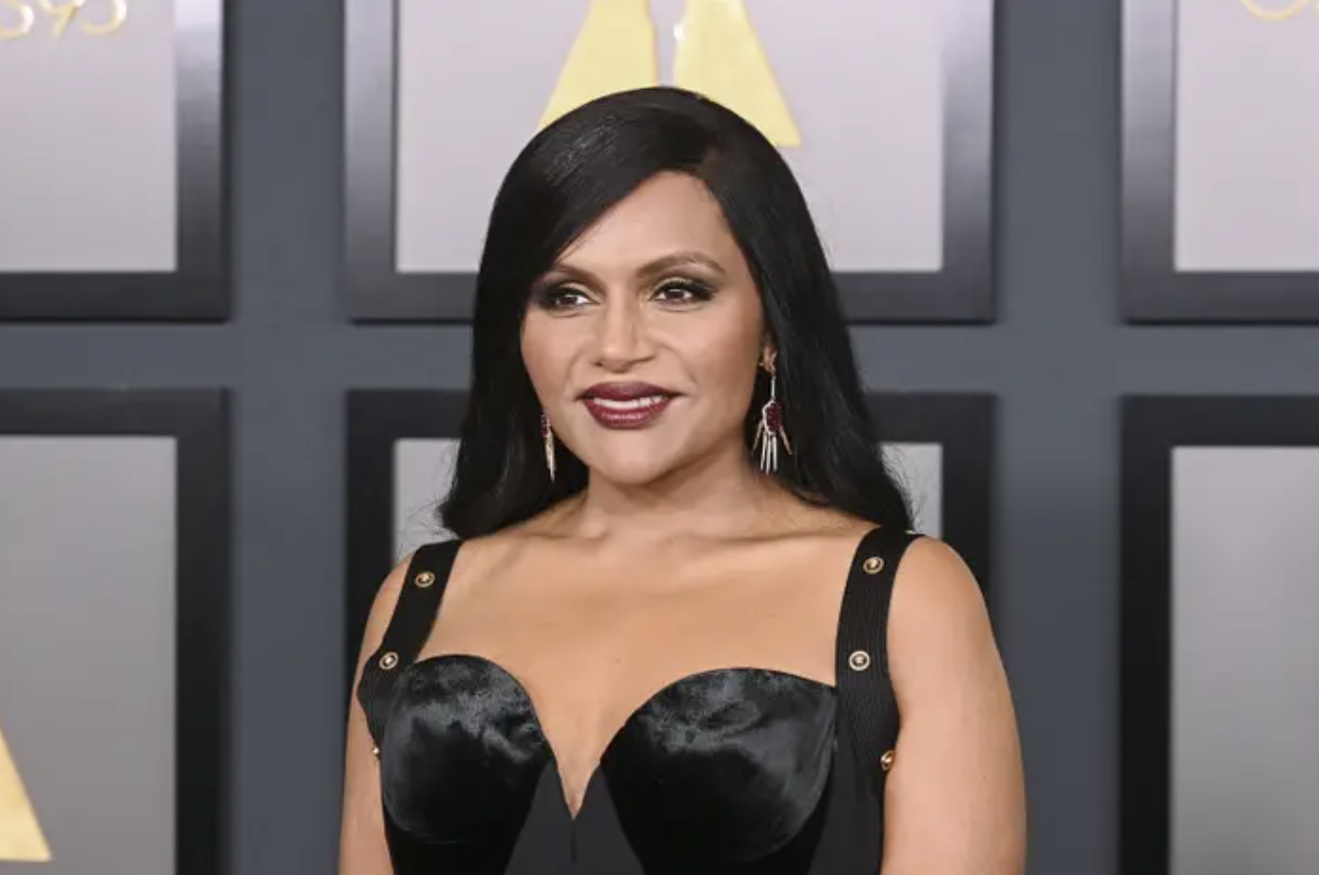 Mindy Kaling smiling in a black dress