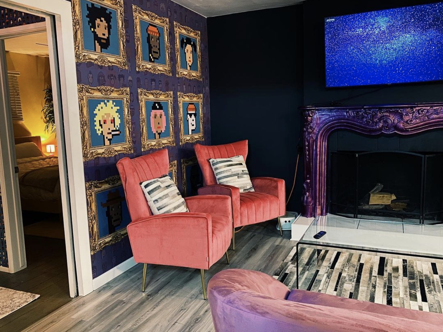 The living room of the Crypto House, which has hot pink armchairs and a shiny purple fireplace