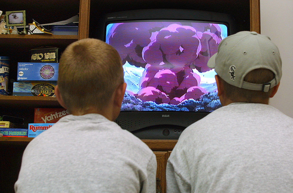 Two kids watching an animated bomb scene on the TV