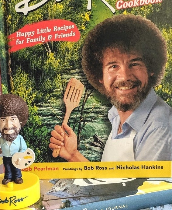 the Bob Ross bobblehead sitting on a stack of books