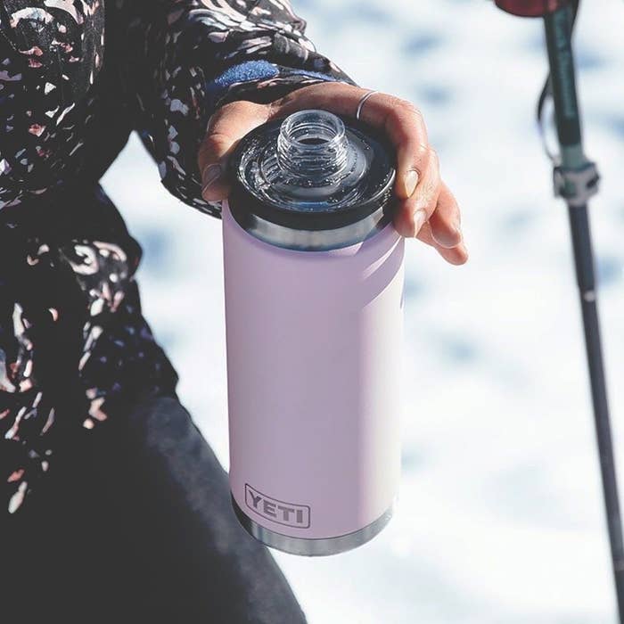 someone holding a yeti water bottle outside with the lid off revealing the drinking spout