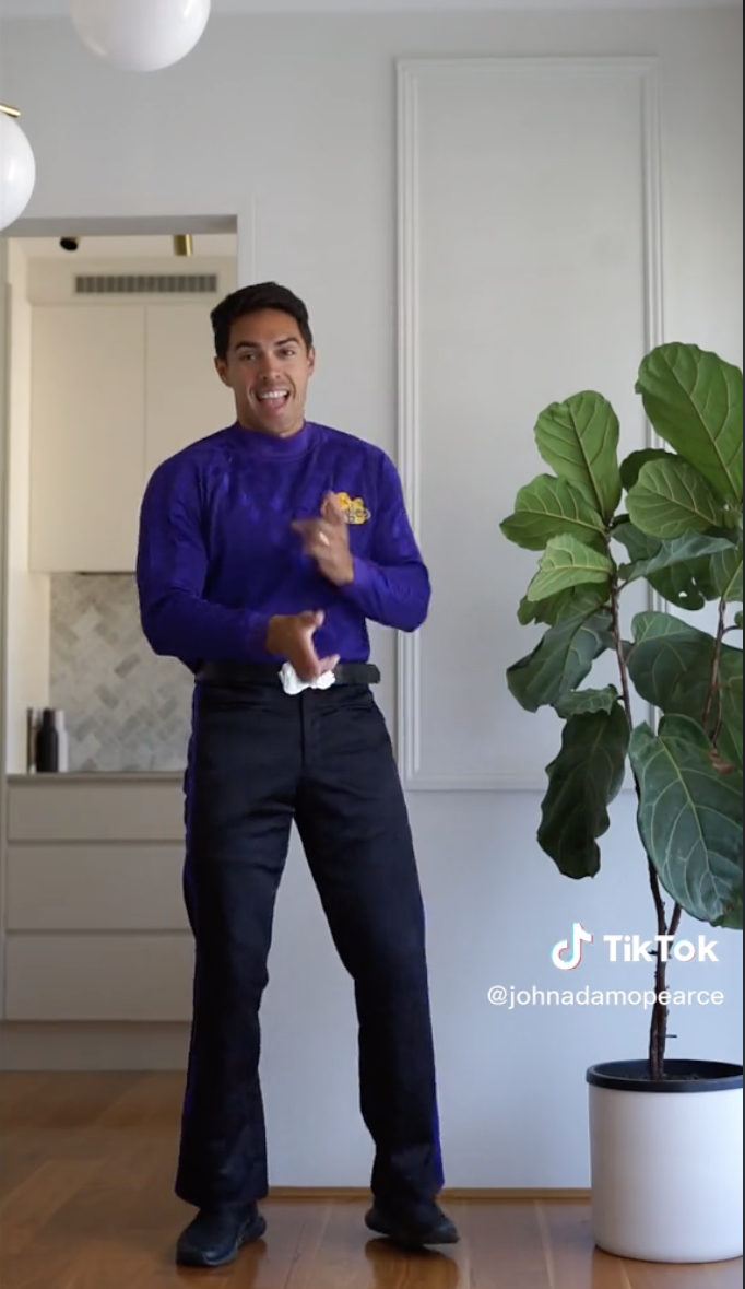 John dancing next to a tall house plant in his Wiggles uniform