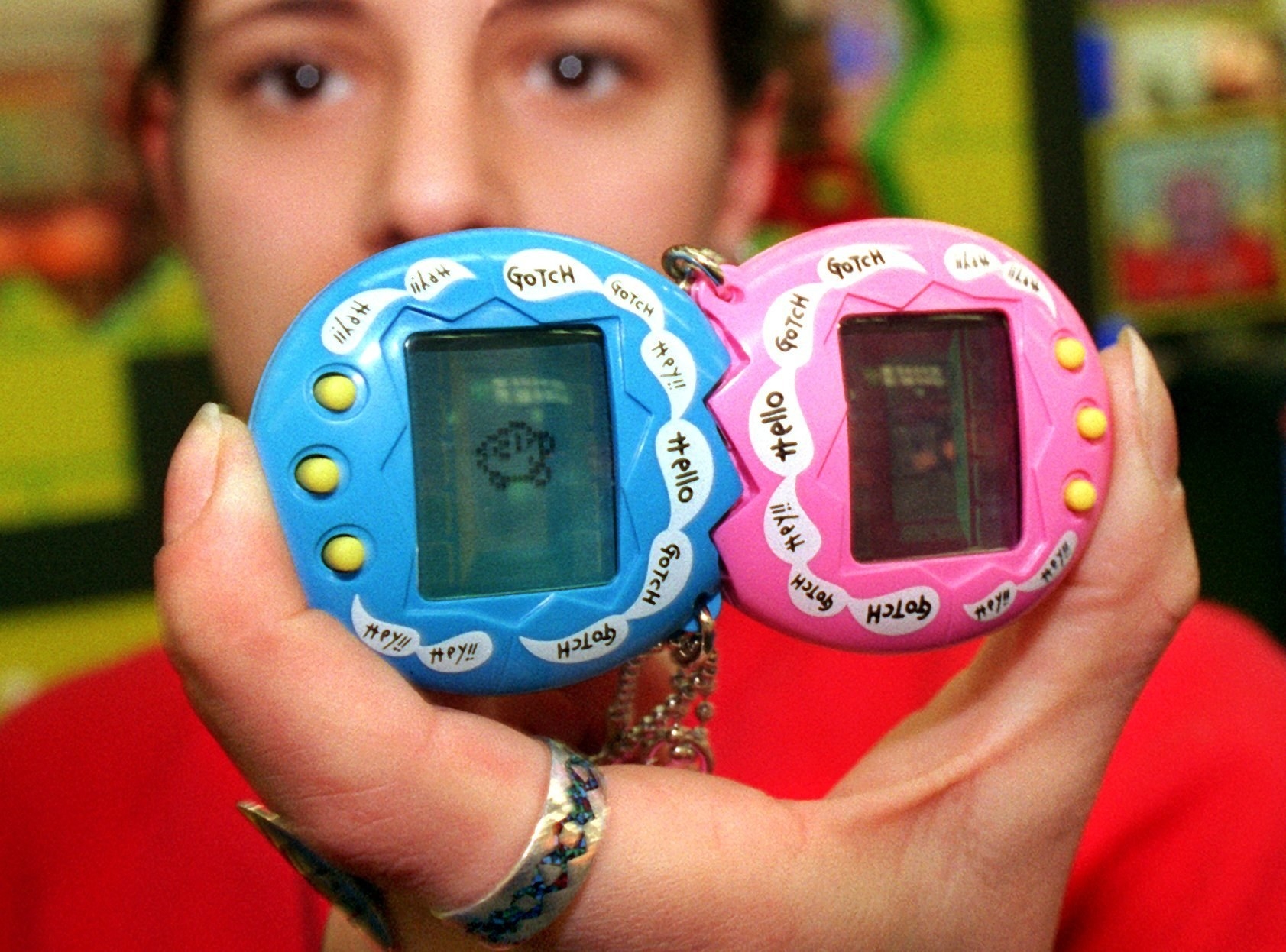 A girl holds up two Tamagotchis