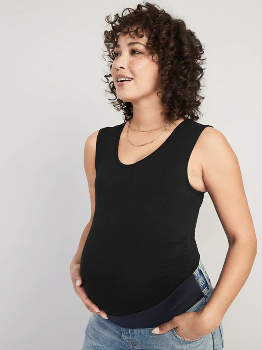 pregnant model wearing the bodysuit holding their belly