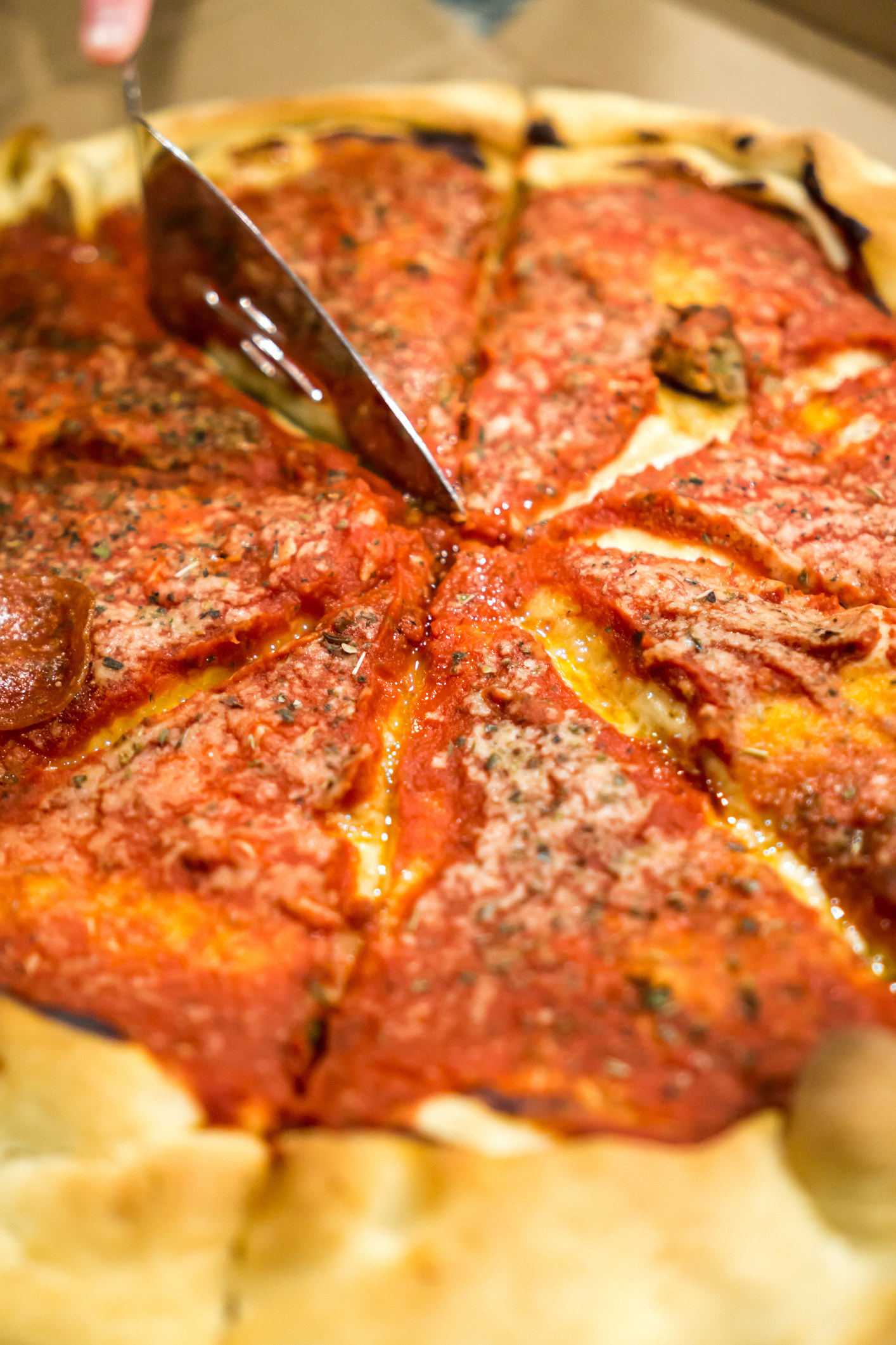 Deep dish pizza being cut with a server spatula.