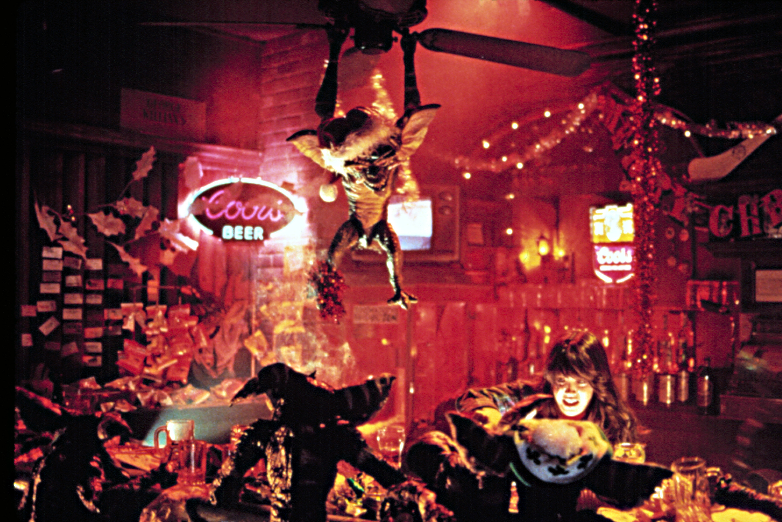 A gremlin swings from the ceiling in a bar