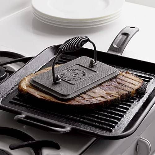 a grill press weighing down a steak on a pan