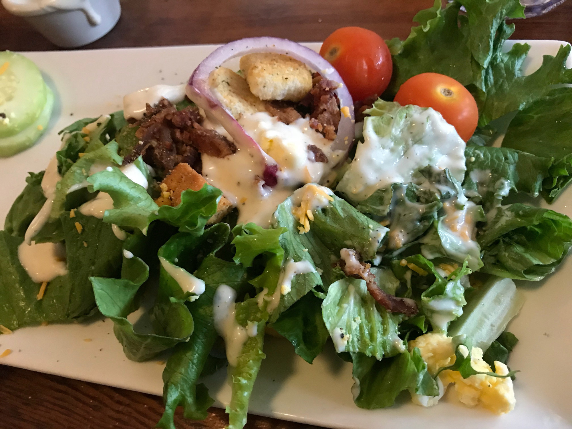 Salad with tomatoes and bacon, croutons, and ranch dressing.