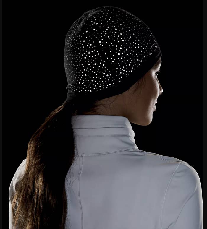 a person wearing the light reflecting beanie in a dark room; reflective spots are visible