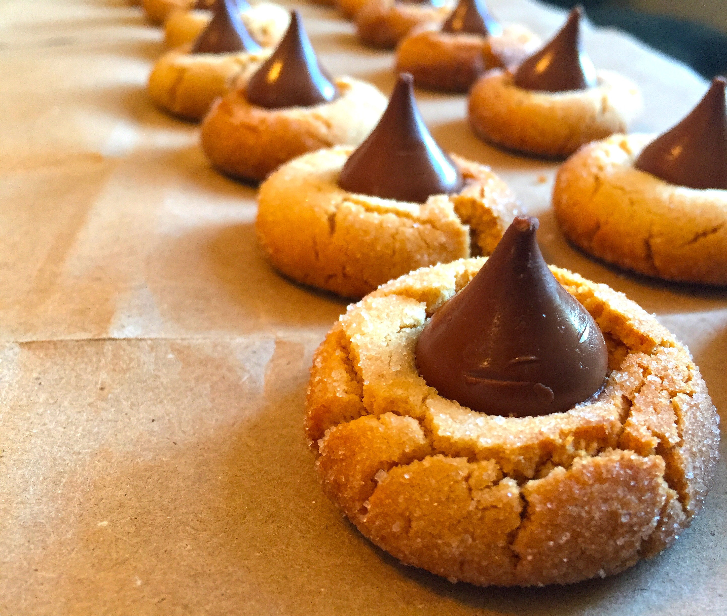 Rows of peanut butter blossom cookies with Hershey&#x27;s kisses on top.