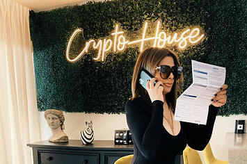 The Crypto House owner Elle Levy sat in front of a neon sign saying 'Crypto House' at the property