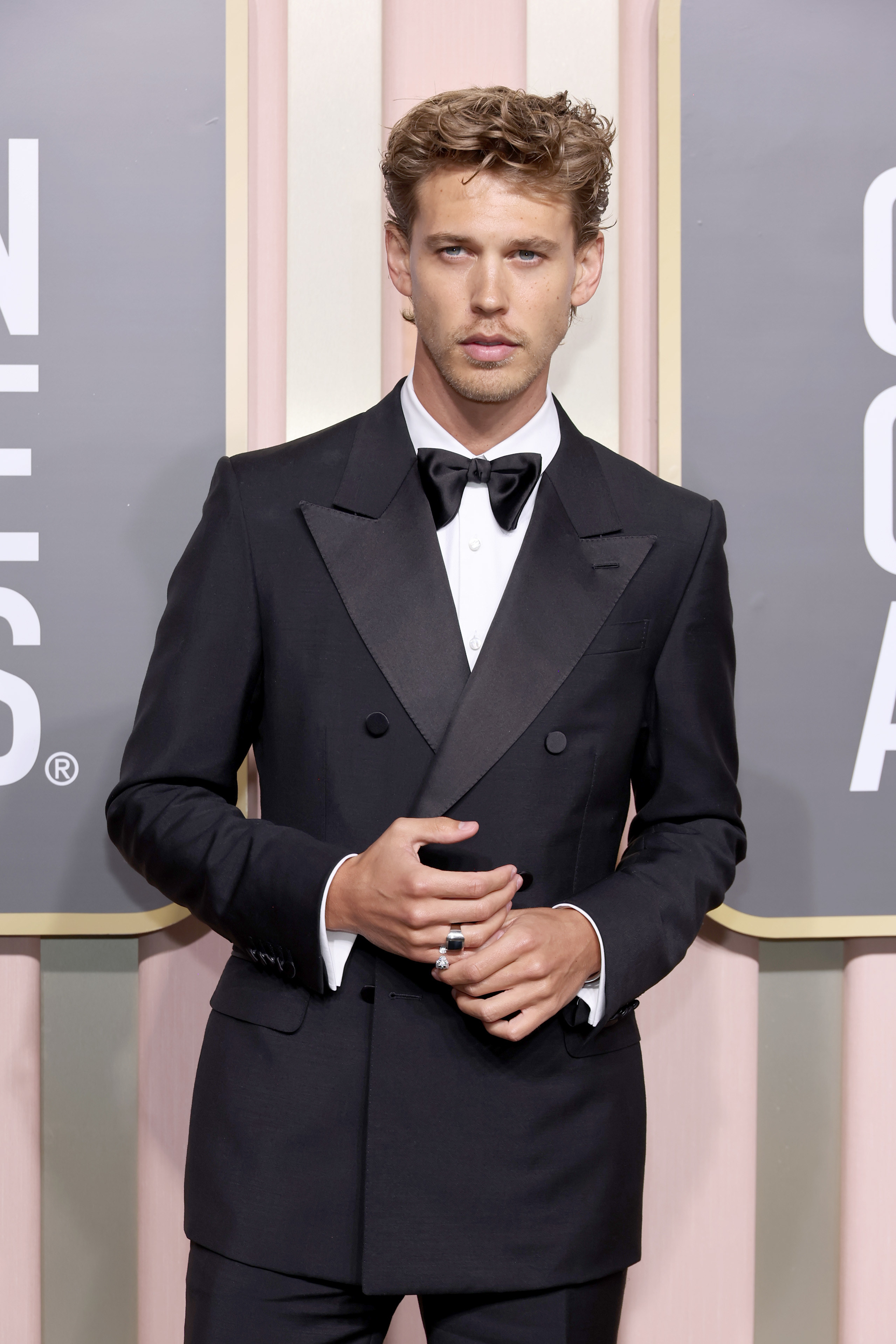Austin in suit and bow tie stands for photographers on the Golden Globes red carpet