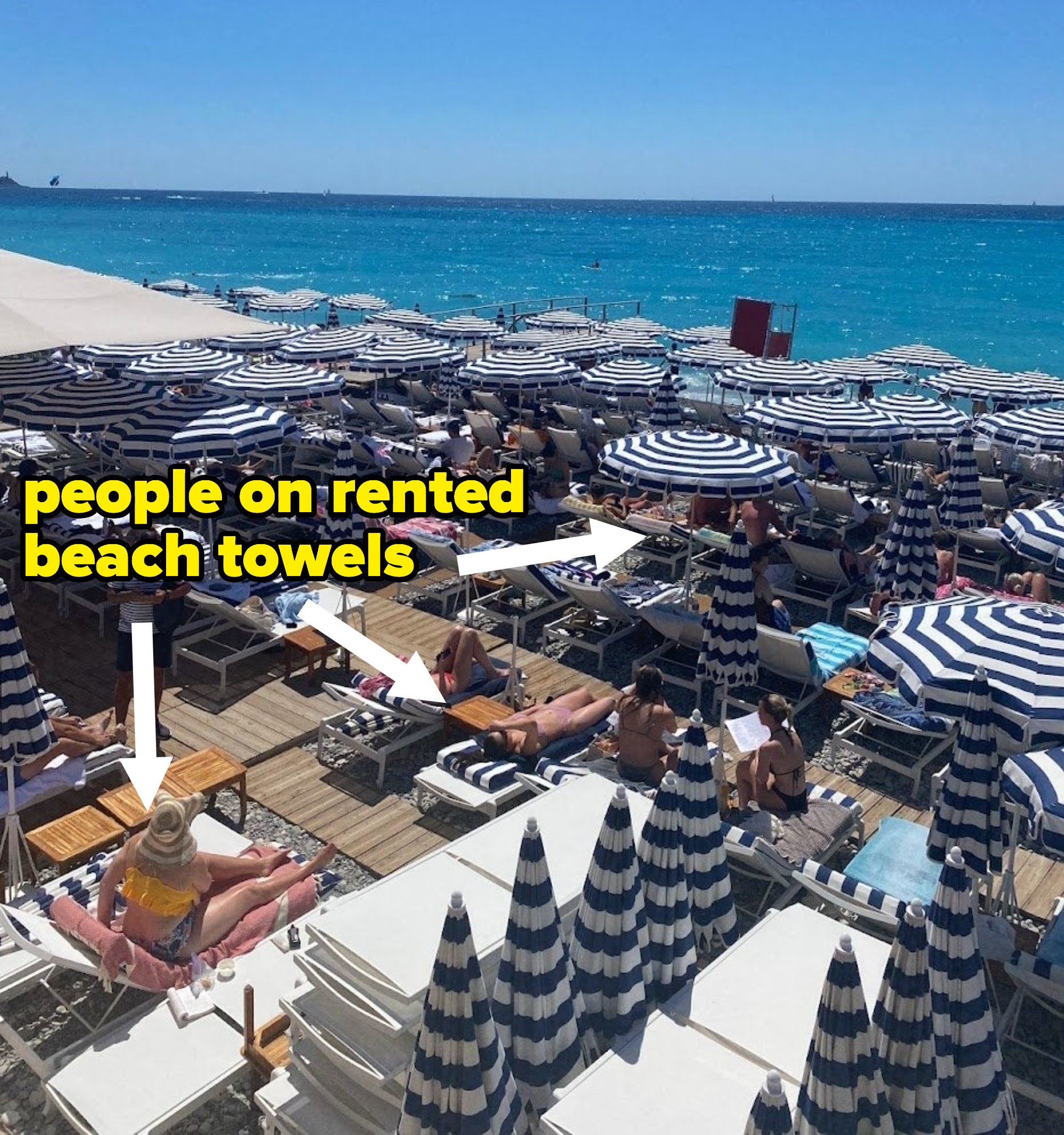 Arrow pointing to people on rented beach towels under an umbrella