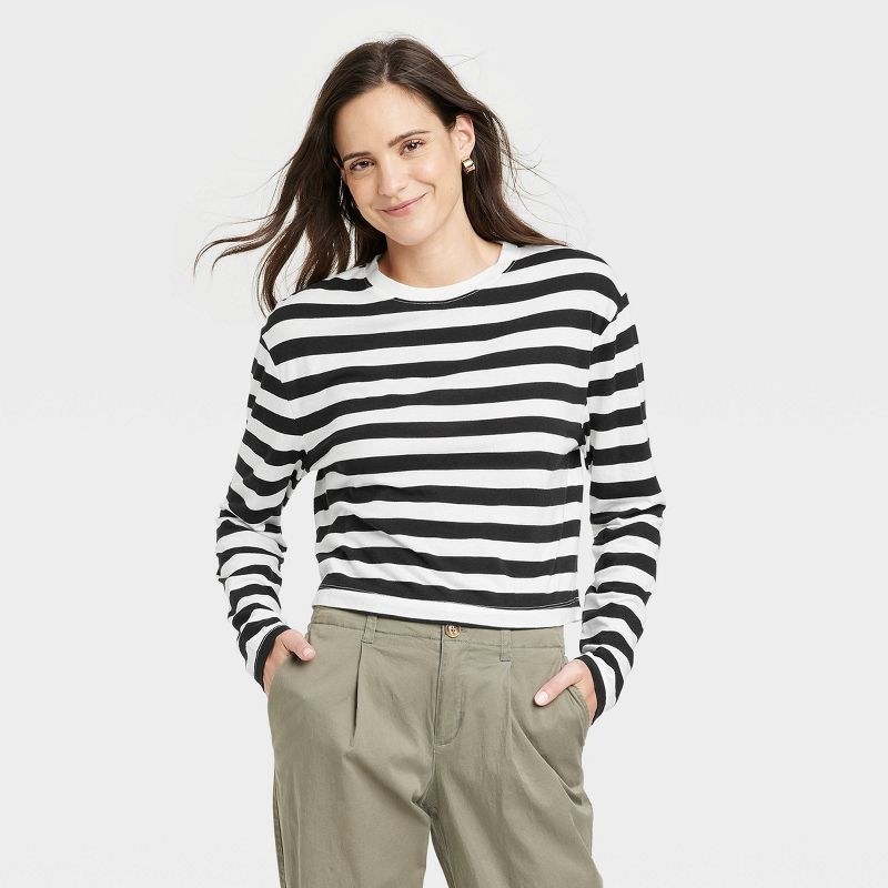 Model wearing black and white striped tee with green pants