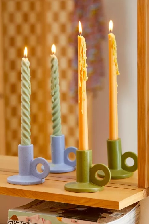 Two colorful candle holders with burning taper candles
