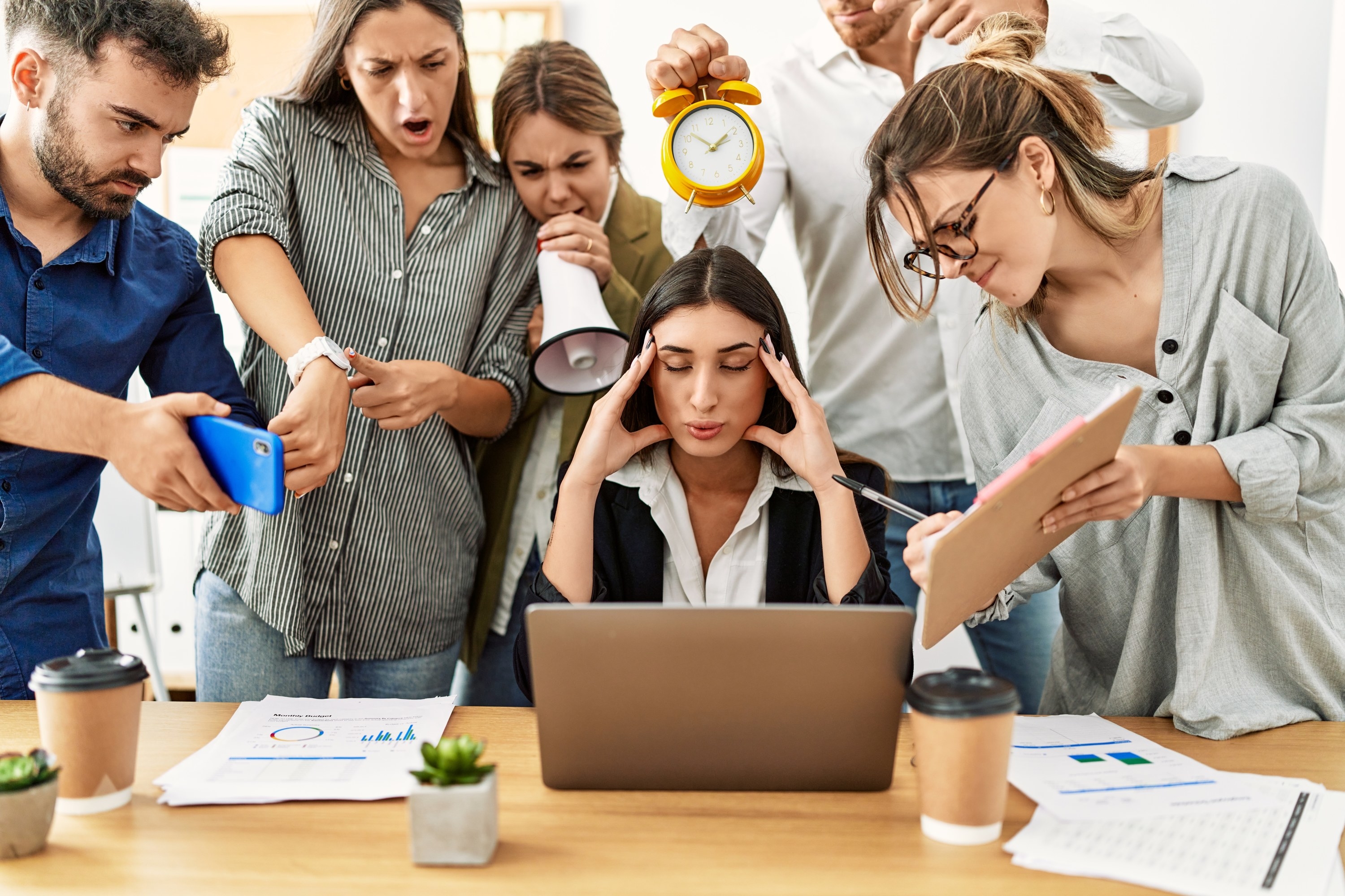 A stressed woman working while surrounded by people