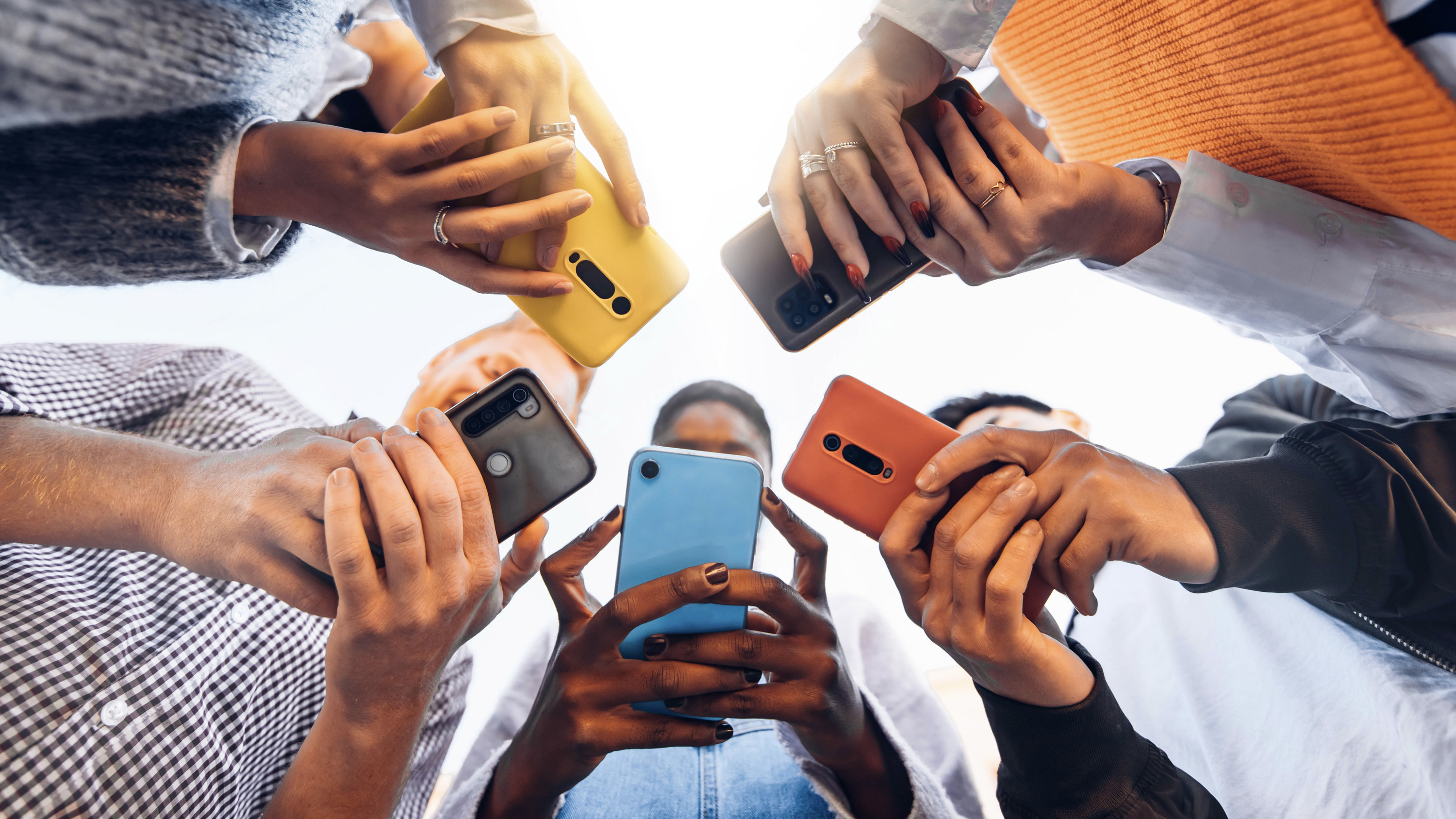 Hands on phones of people standing in a circle