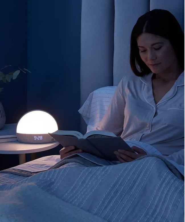 A model reading in bed next to the light
