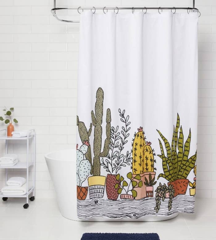 A white shower curtain with illustrations of succulents on it