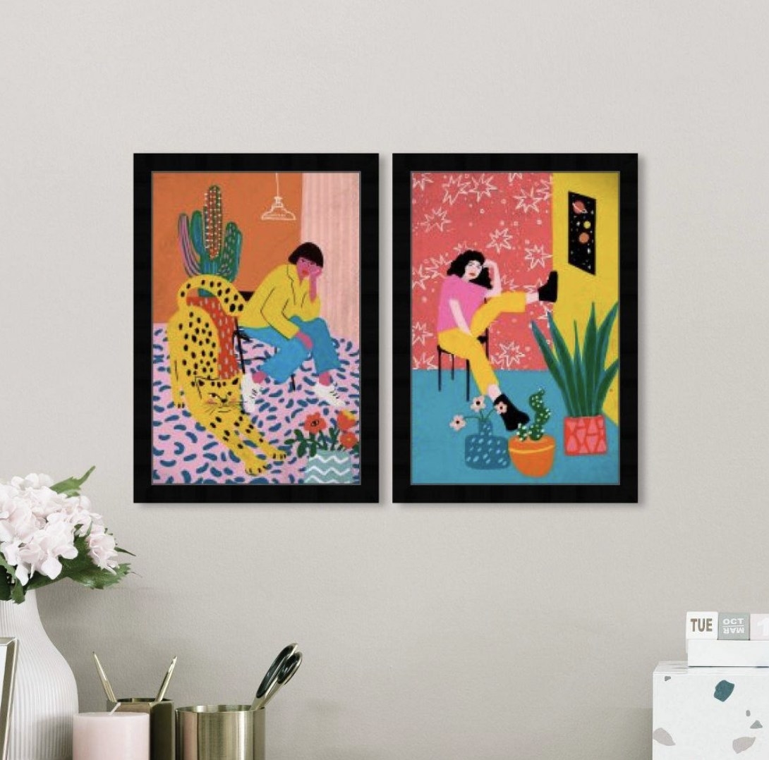 two very colorful art prints hanging on a beige wall