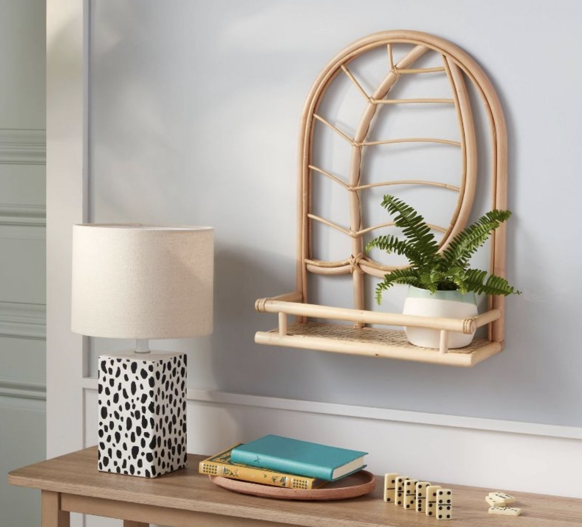 A rattan shelf with a leaf design displaying a small plant