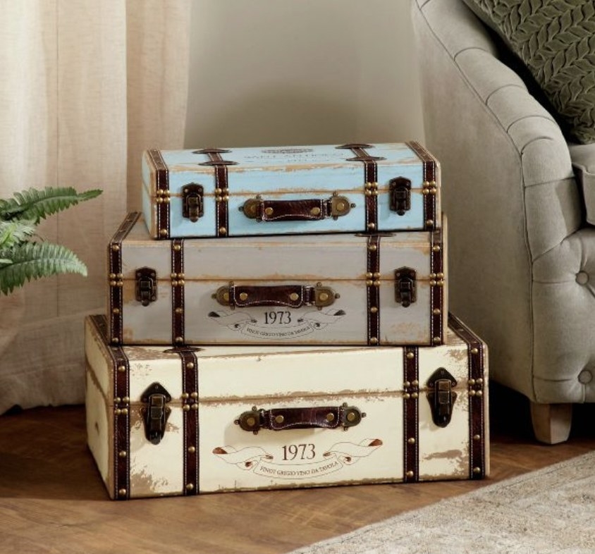 Three distressed trunks stacked on top of one another on a wooden floor