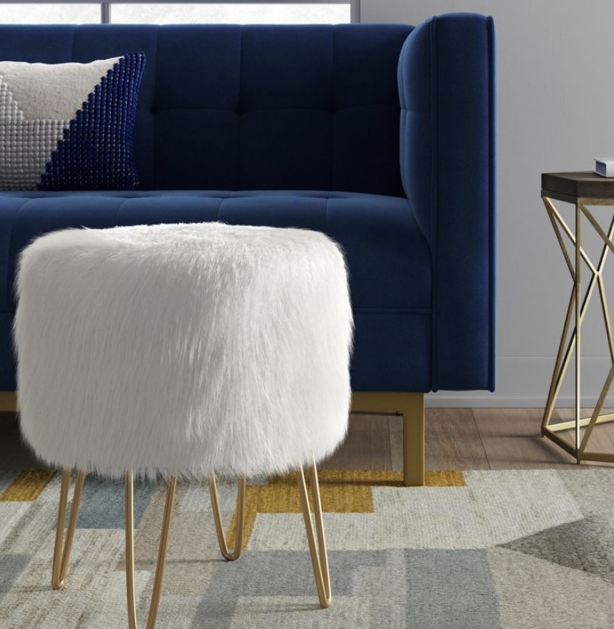 a white fuzzy ottoman in front of a dark blue couch