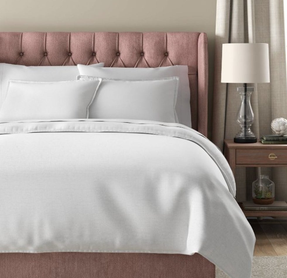 A pink bed with white linens