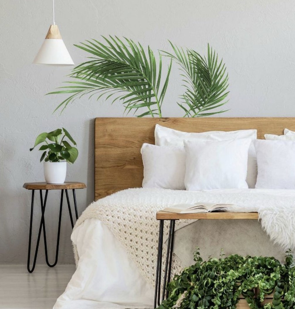 A bed with two palm leaf wall decals behind it