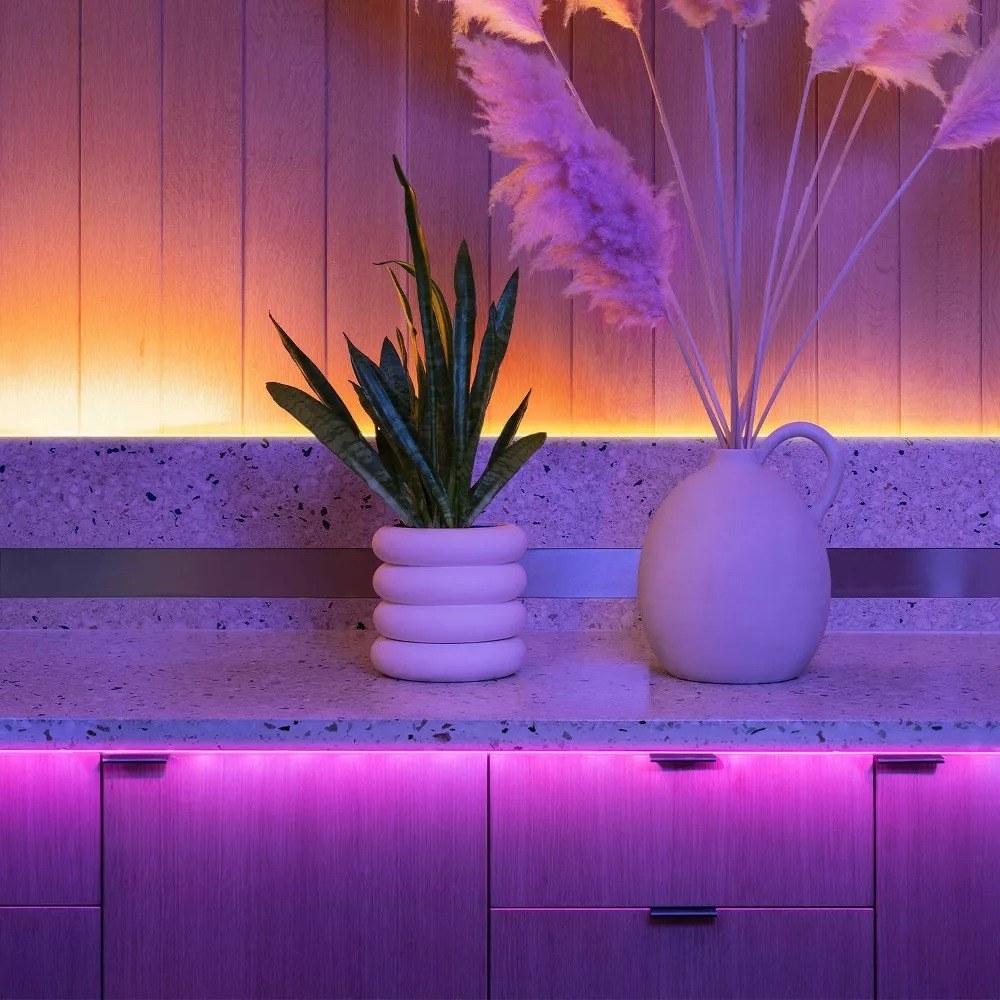 The purple lights glowing below a tabletop with two vases with decor above