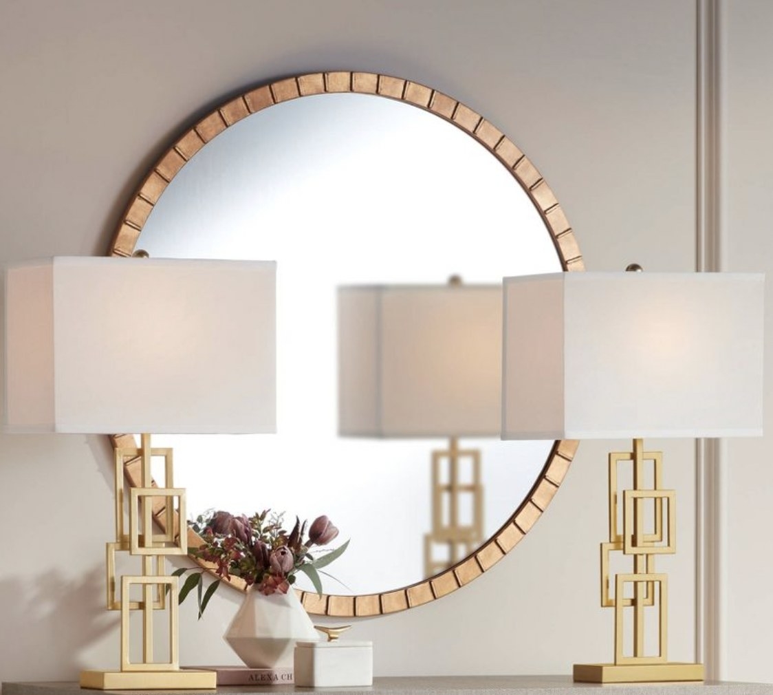 two mid-century modern style lamps in front of a round mirror