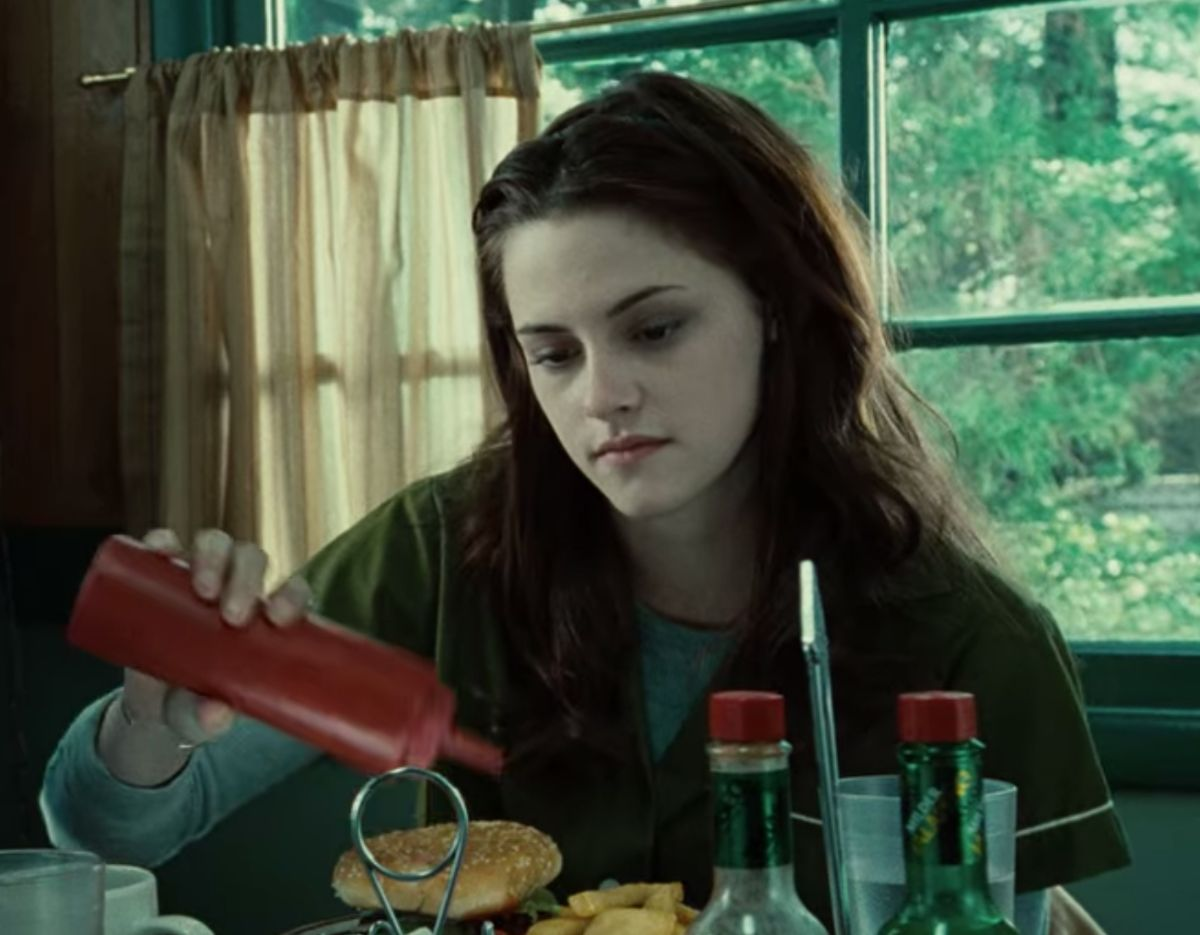 A teenager girls shakes a ketchup bottle