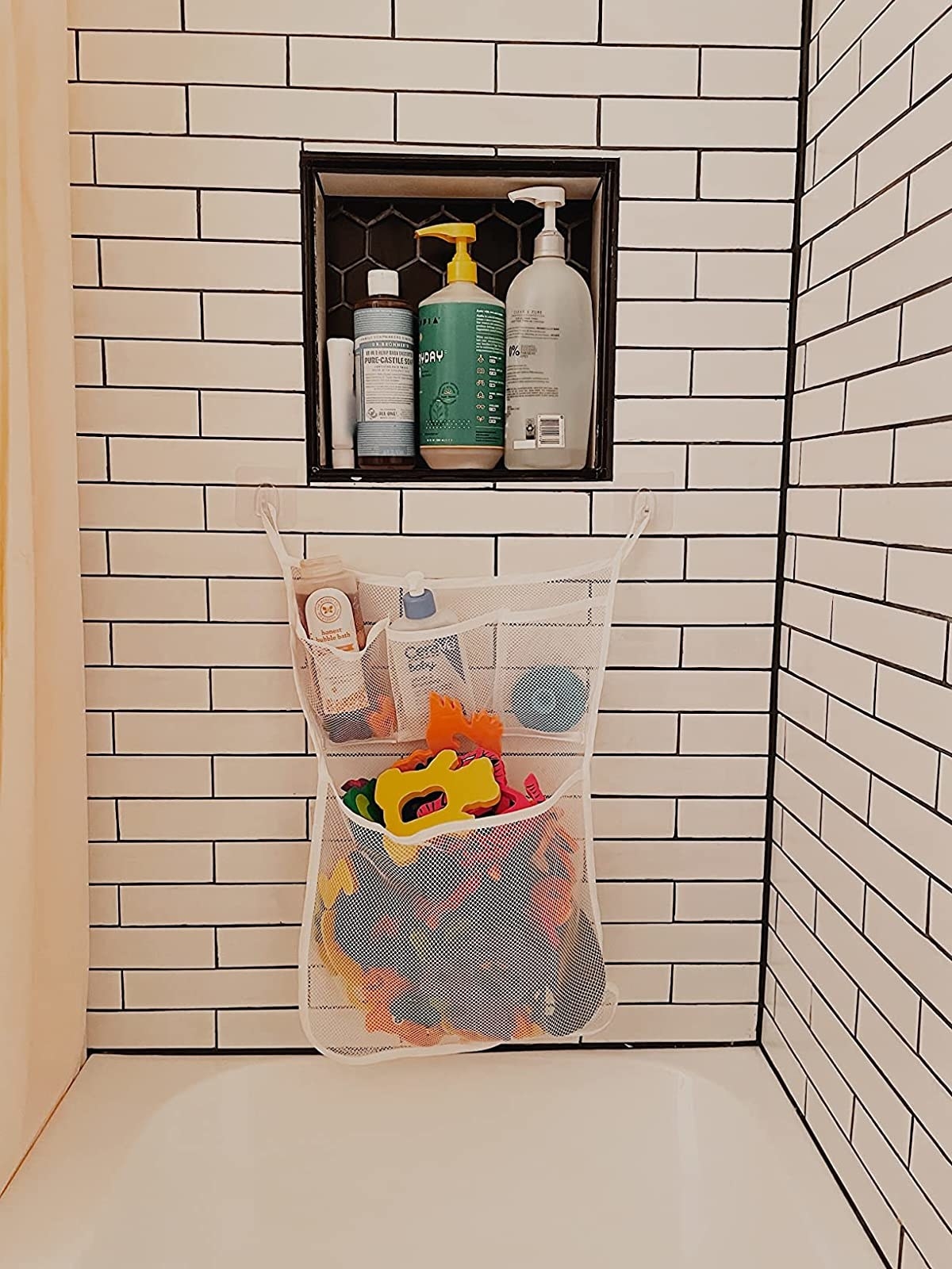 Reviewer&#x27;s photo of the mesh organizer attached to a bathtub wall