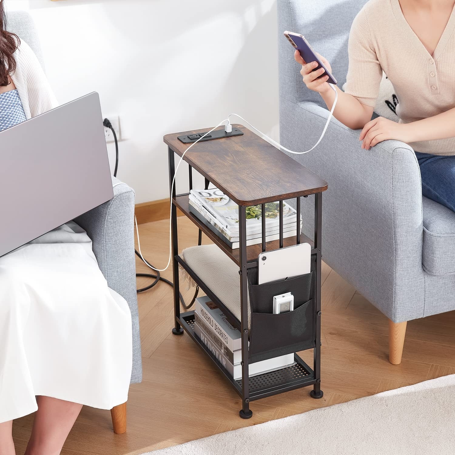 two people with devices plugged into the side table while they work