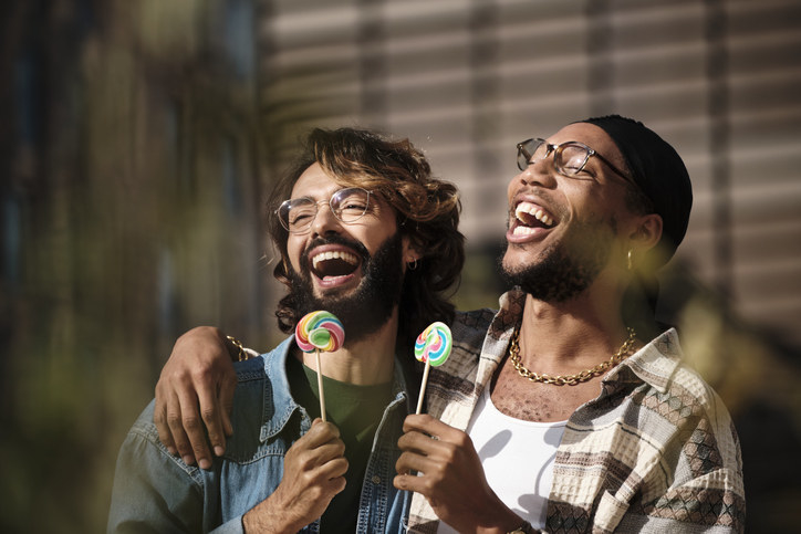 two men laughing with holding lollipops