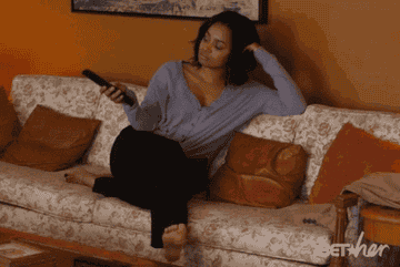 black woman holding a remote, flipping through channels