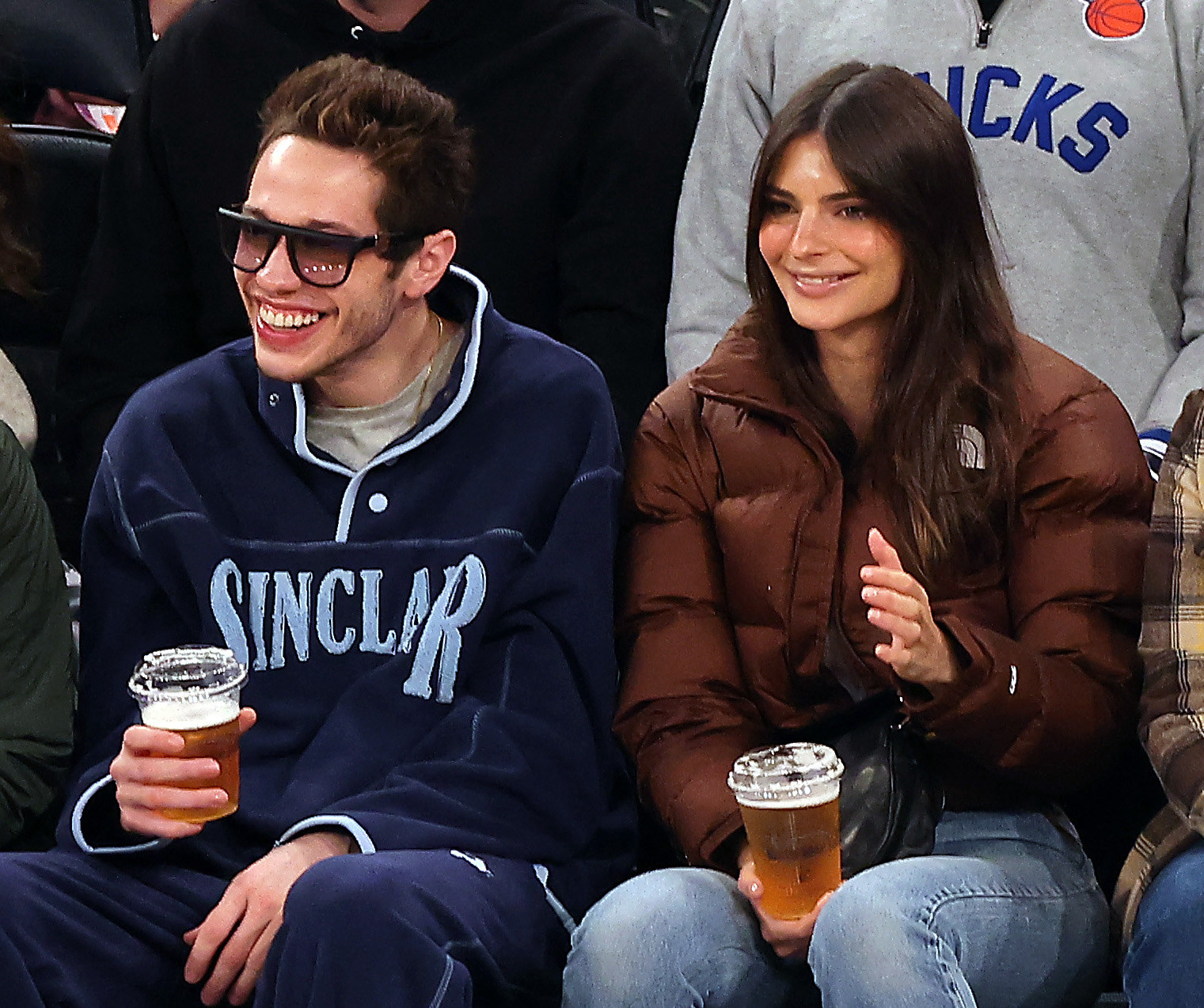 pete and emily courtside drinking beers and smiling