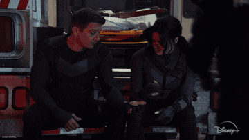 hawkeye and kate sit on the back of an ambulance