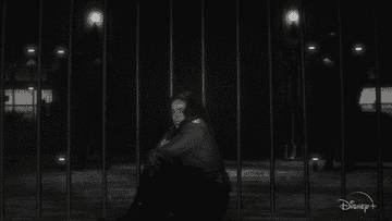 girl sits on the ground in what looks like a jail cell, laughs