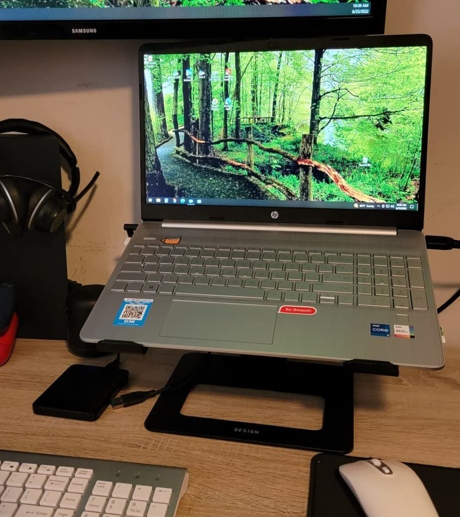 Reviewer with stand set up to elevate laptop with separate keyboard and mouse beneath on desk