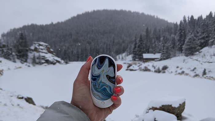 Reviewer holding the mosaic patterned hand warmer outside on winter hike