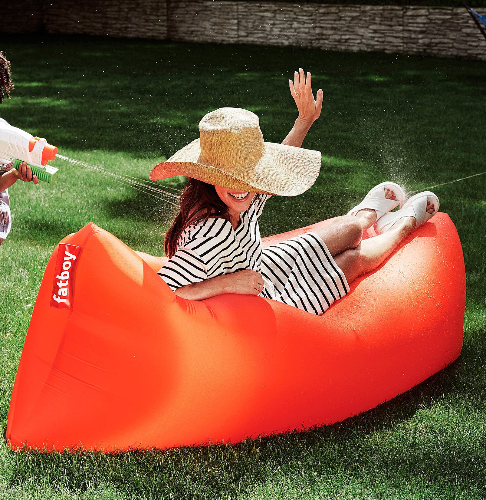 a person getting sprayed with water guns while lounging on the inflatable lounger