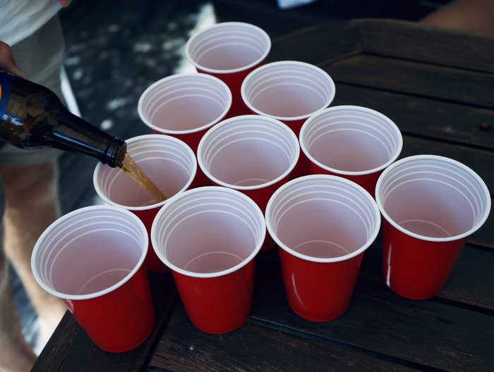 Someone pouring alcohol into red Solo cups
