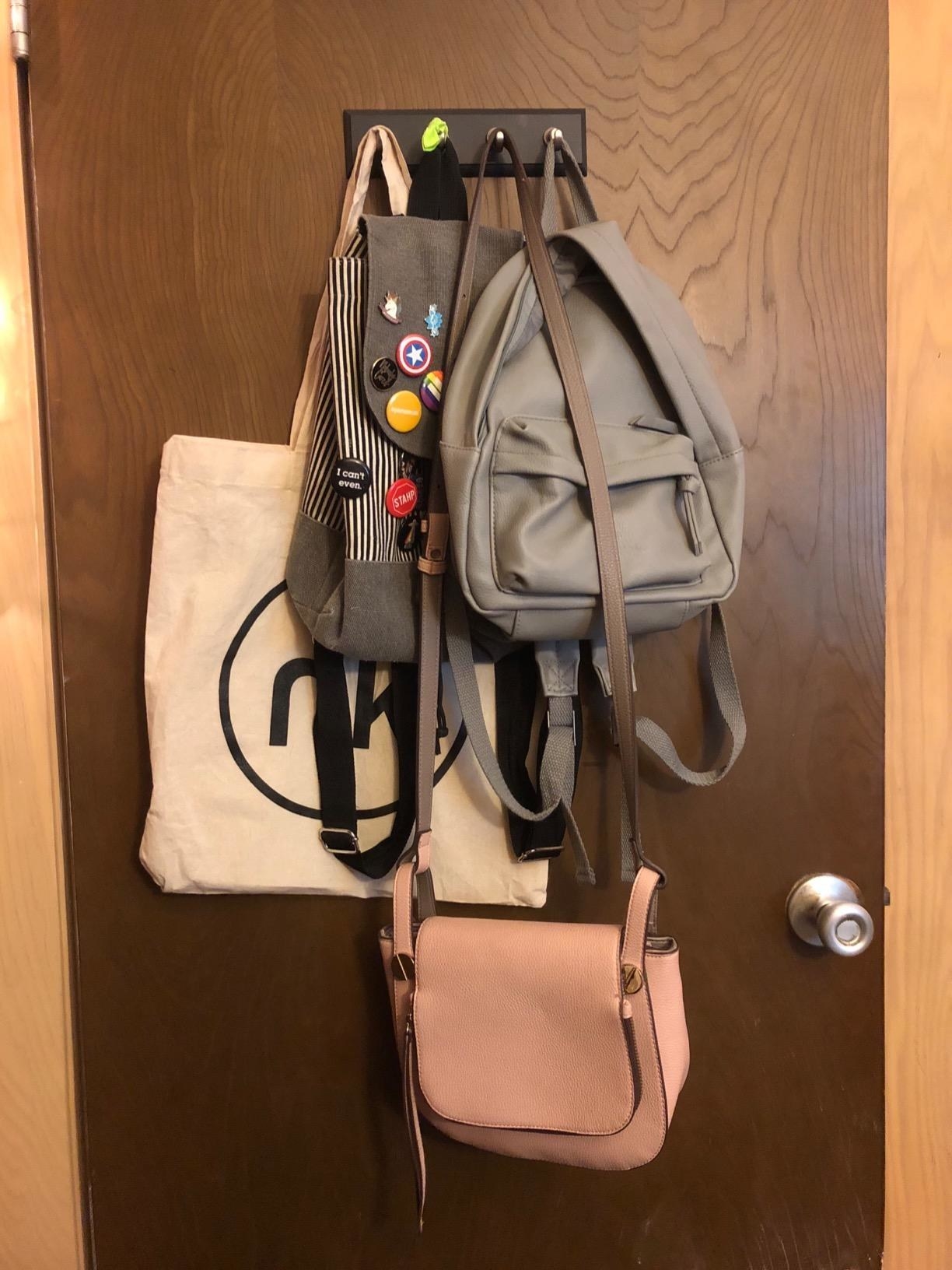 A reviewer&#x27;s bags hung on the four hooks attached to a door