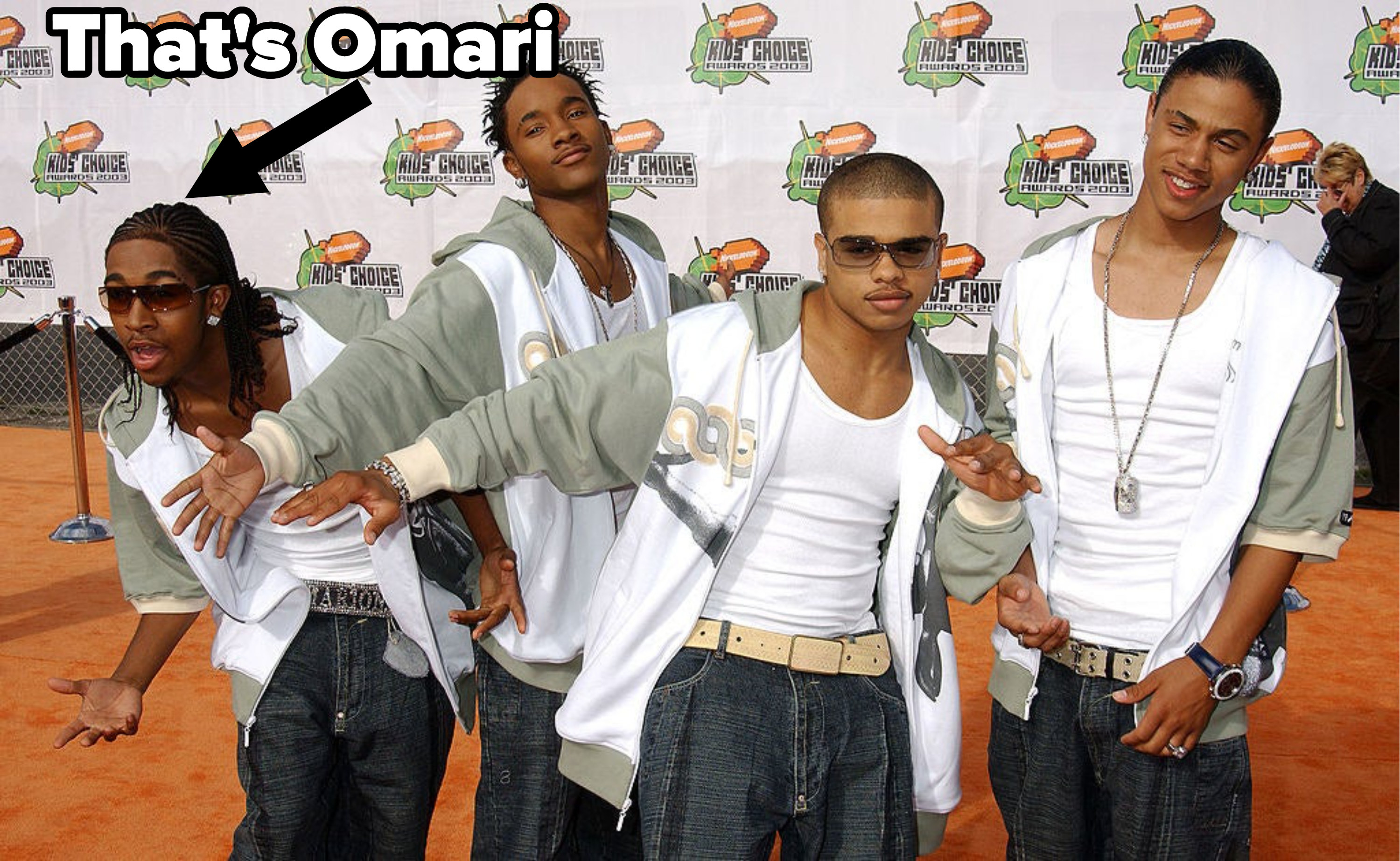 B2K doing funny poses on the orange carpet of the Nickolodeon Kids Choice Awards. The group members are wearing matching tanks, unzipped hoodies, and jeans