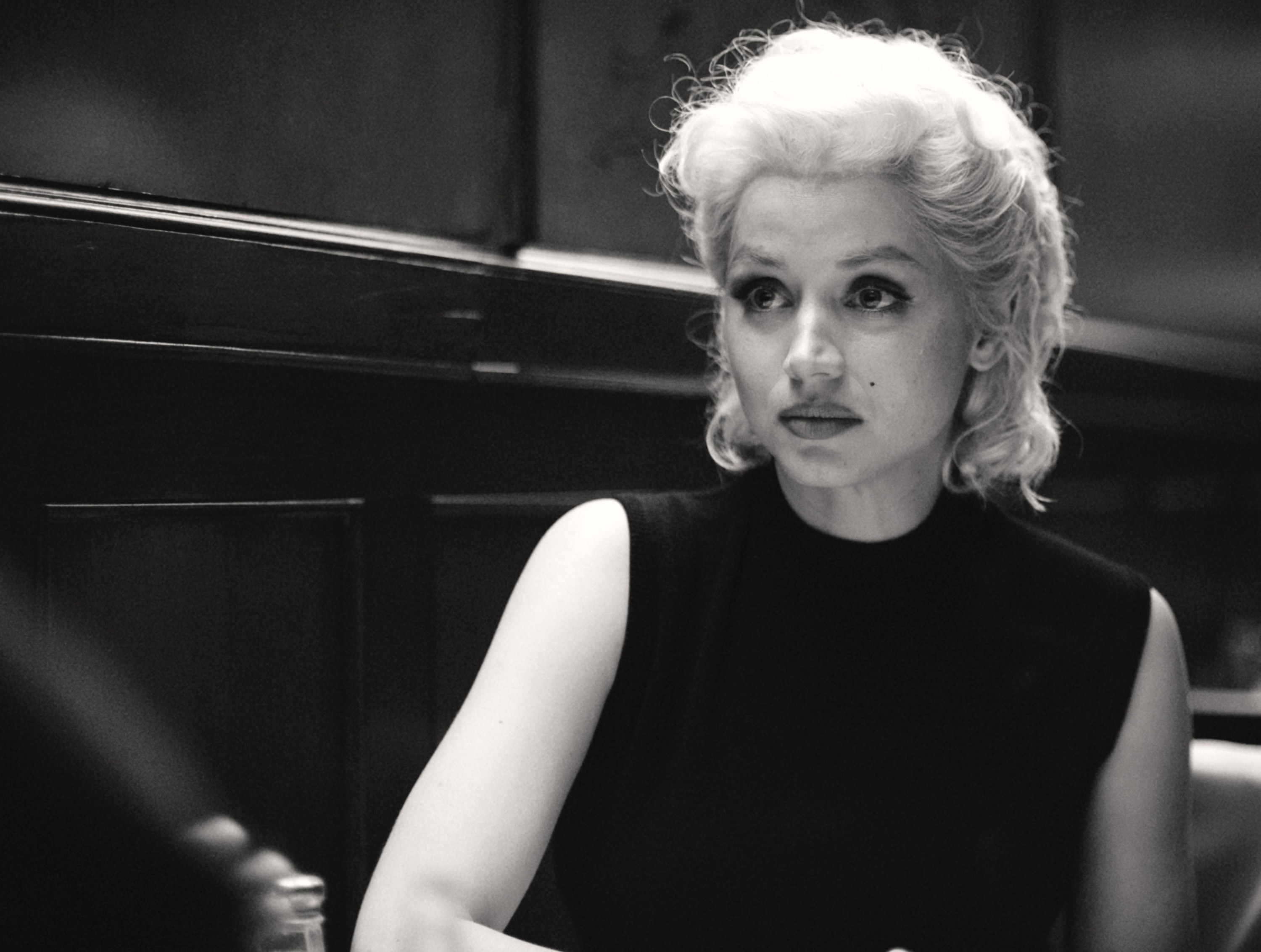 Ana as Marilyn sitting and facing someone in a scene from &quot;Blonde.&quot; Ana is wearing a blonde wig and a sleeveless top