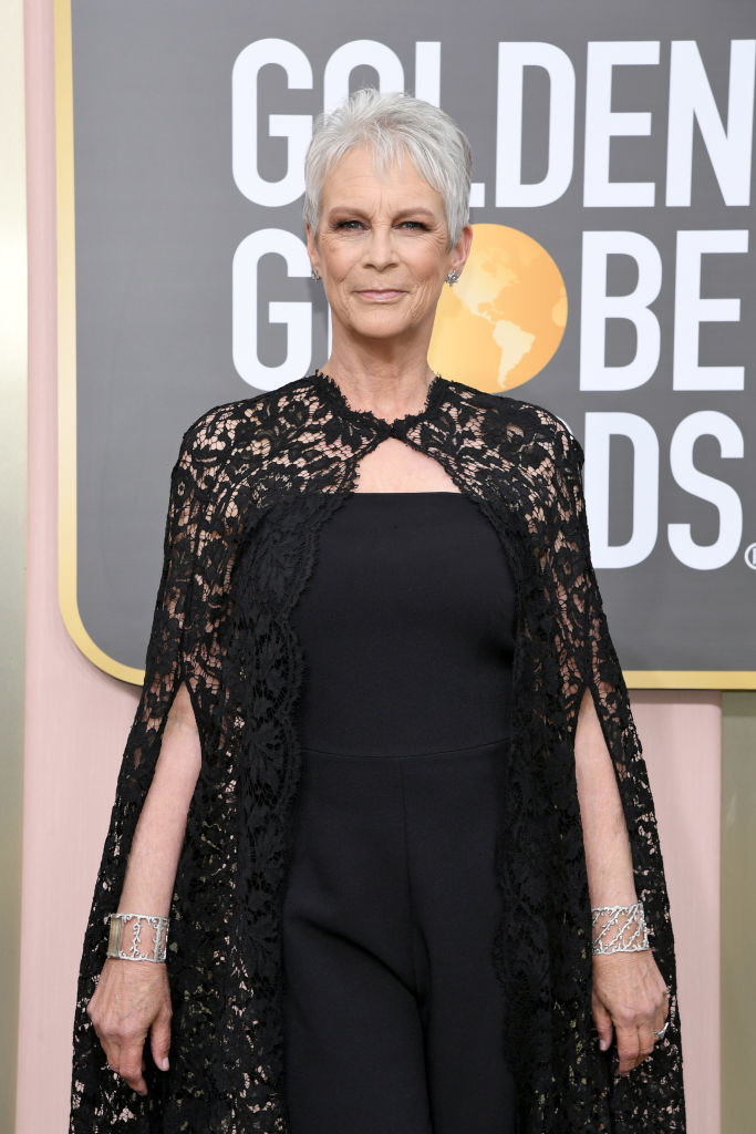 Curtis wears a strapless dress with a lace cape as she poses on the Golden Globes red carpet
