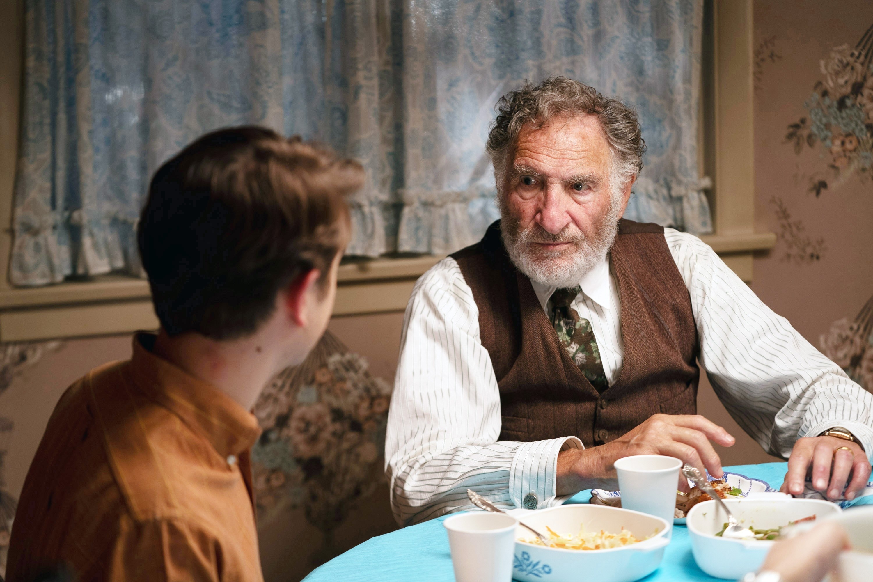 Hirsch looking at another person at the dinner table in a scene from &quot;Fabelmans&quot;