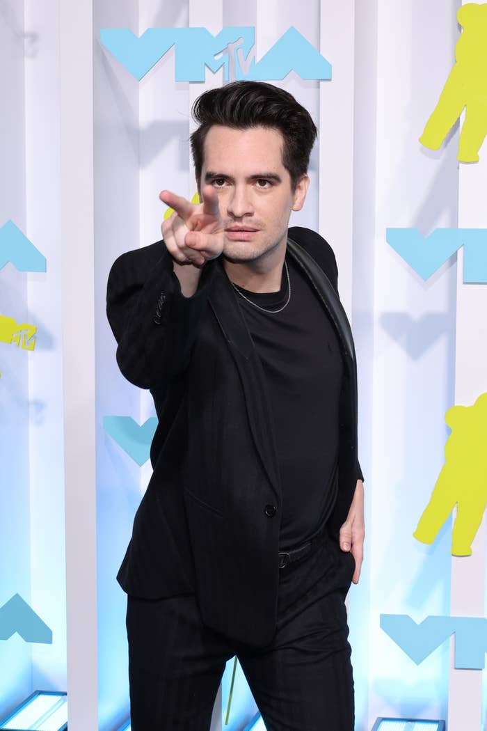 Brendon pointing his pointer and middle fingers on his right hand at photographers as he poses on the red carpet