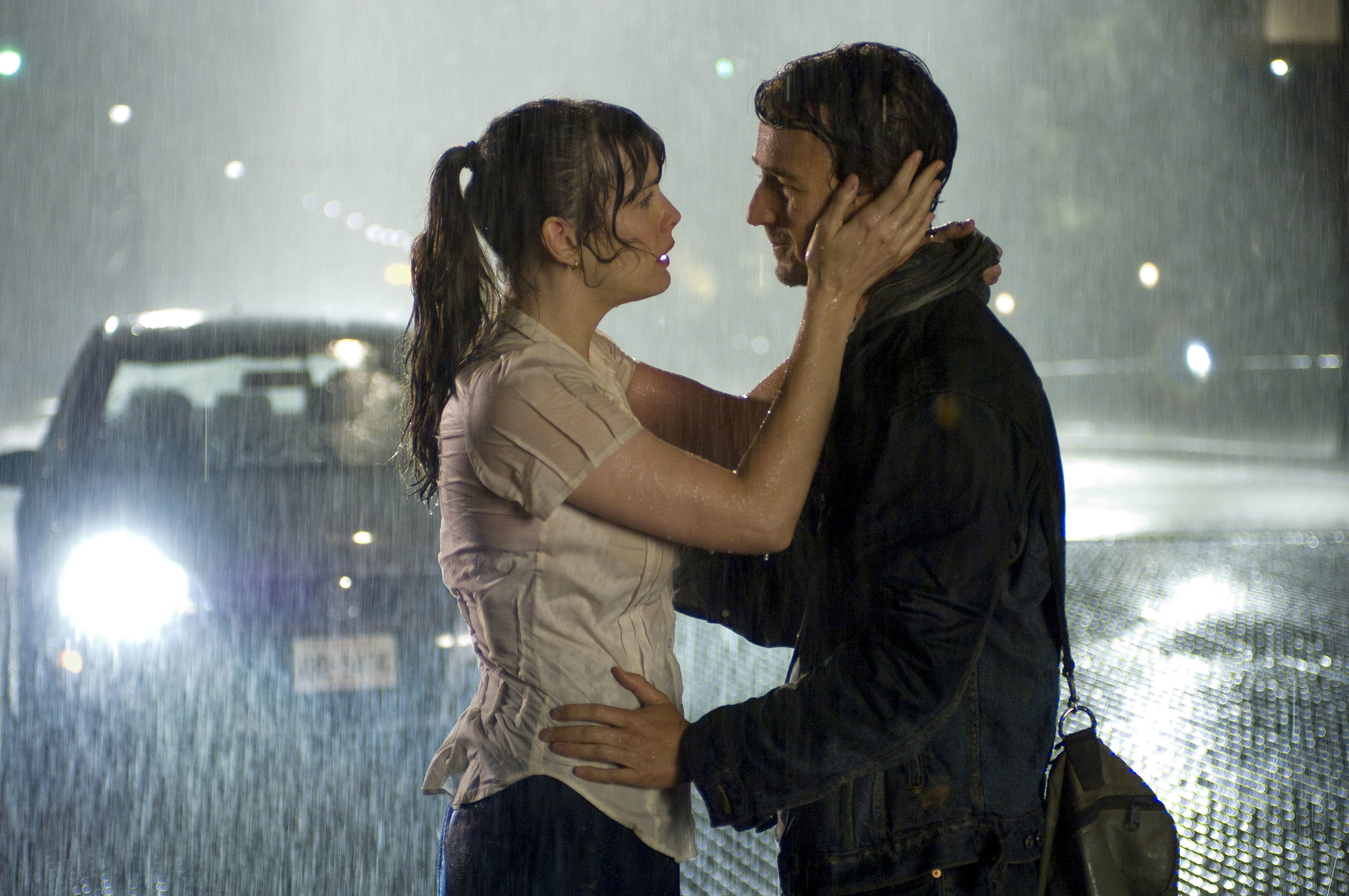 A man and woman standing in the rain holding each other